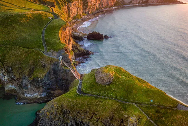 Aerial view of a green headland and winding path above the Atlantic